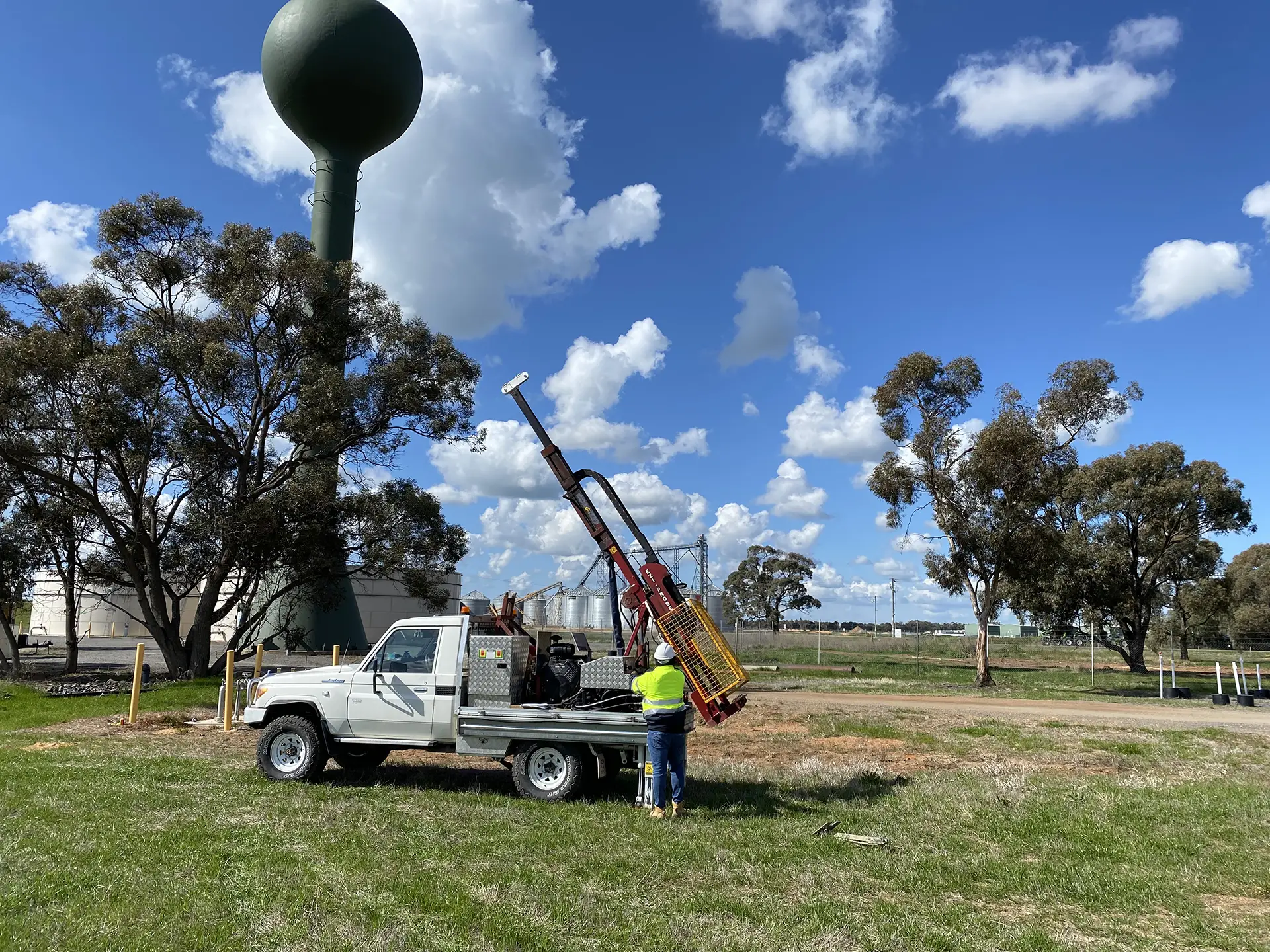 A Toyota Landcruiser with a geotechnical drill rig attached, parked at an industrial site in Melbourne, Australia. A geotechnical engineer prepares for site classification.