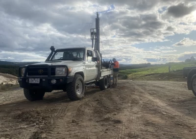 A determined geotechnical expert in orange high-visibility gear studies soil samples, demonstrating Probe Geotechnical Services' dedication to slope stability analysis in Melbourne.